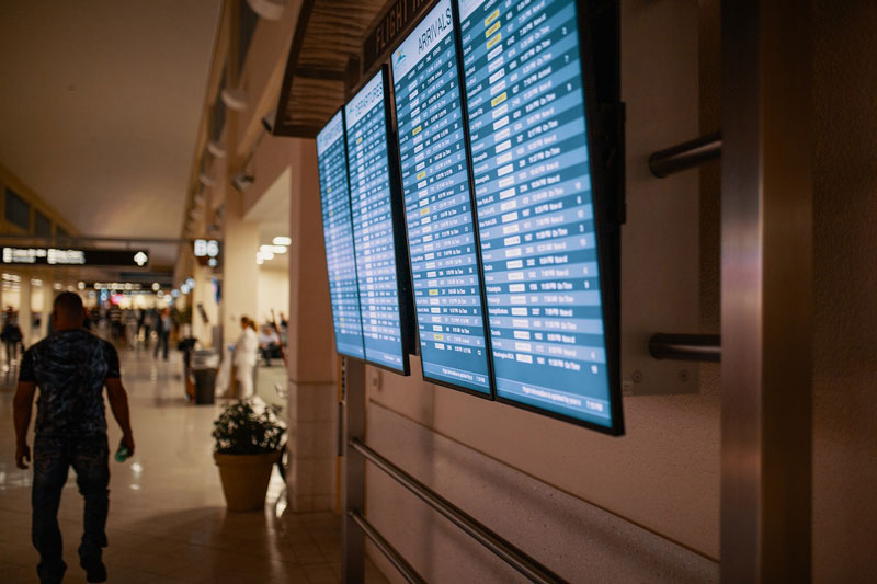 Image shows airline flight schedules on flat screen televisions